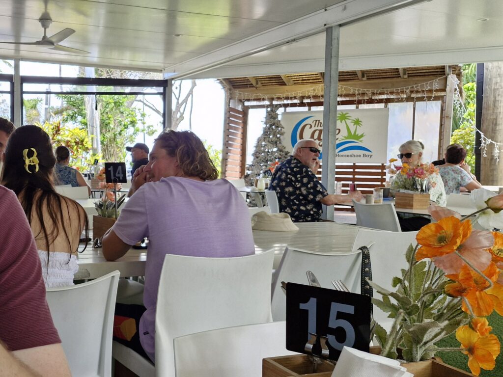 Customers enjoying a relaxed dining experience at a tropical-style café with bright flowers and casual seating.