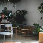 Man working on laptop in a leafy modern cafe with natural light and minimalist decor