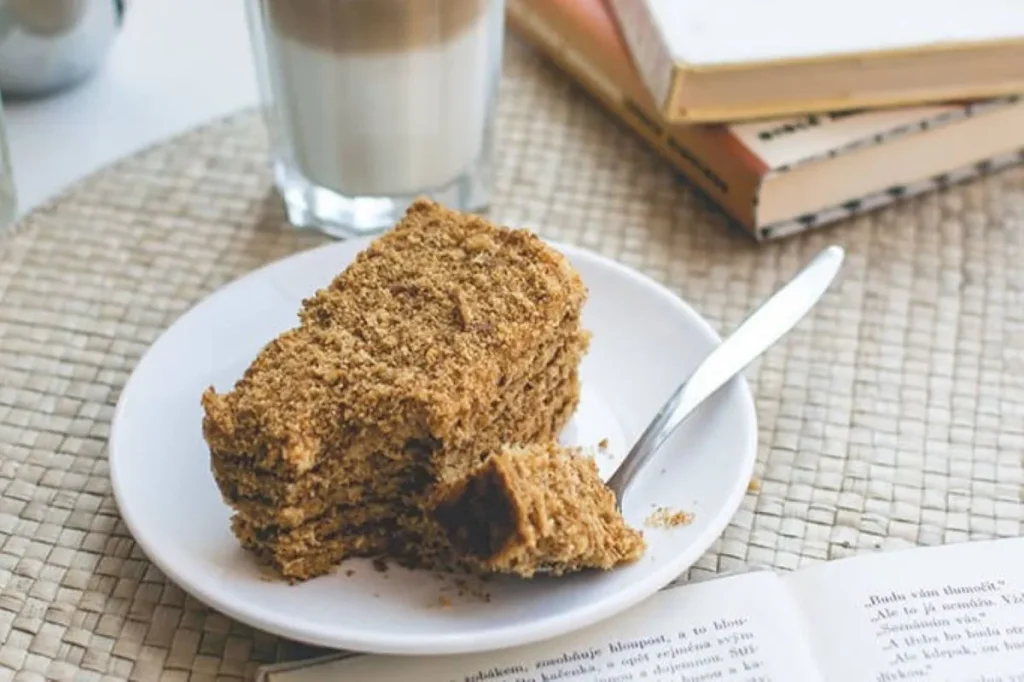 Fresh slice of cake served with coffee on a table in a relaxed café setting, highlighting the customer experience