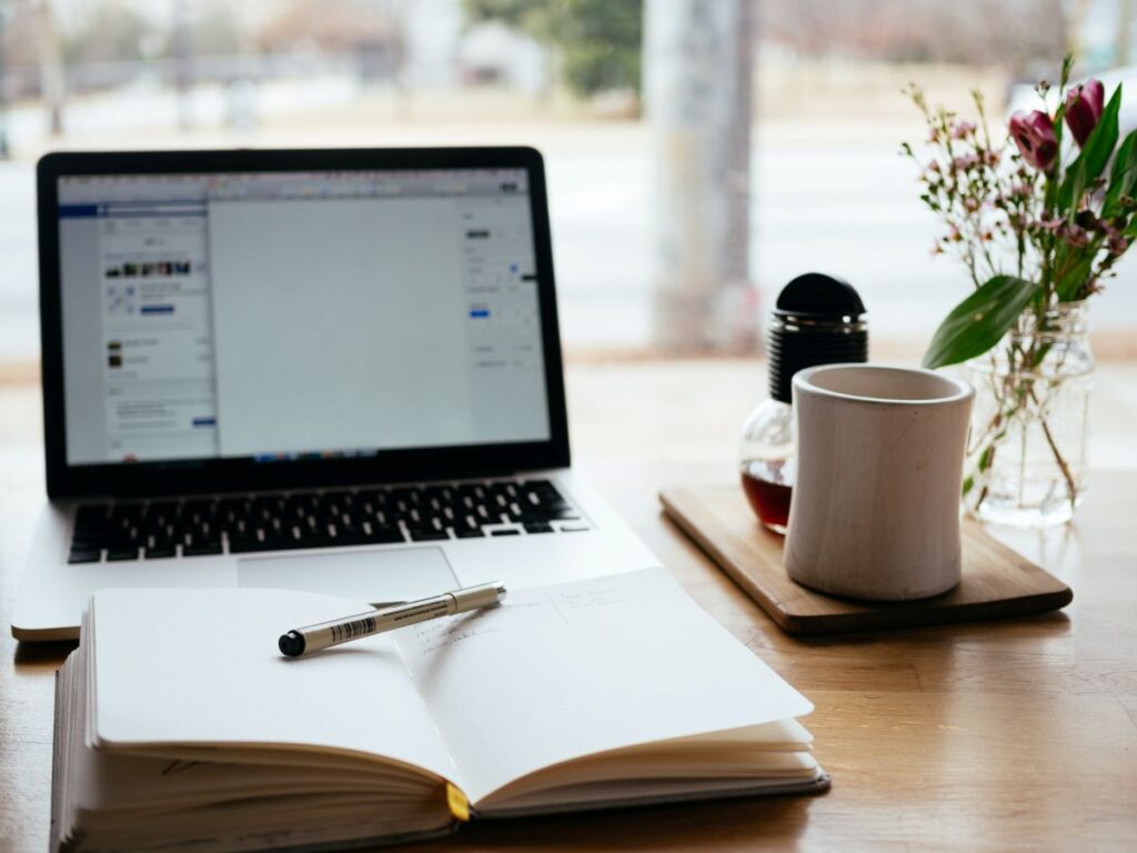 Laptop, notebook, and coffee on a desk representing café business planning and operational strategy
